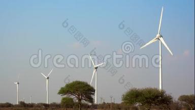 风力涡轮机生产环保的绿色、清洁的电力，底部有树木，蓝天和云层